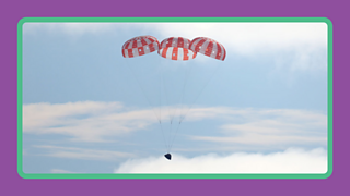 Parachutes on the Columbia module of Apollo 11 slow it down before it splashes down into the Pacific Ocean